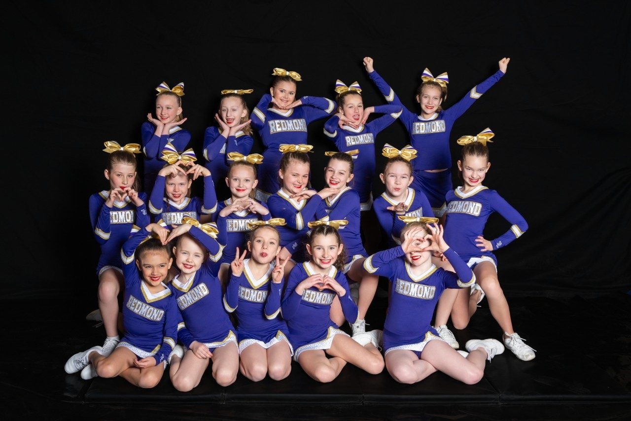 Mountain Peak youth cheer team posed with heart hands in a studio photo